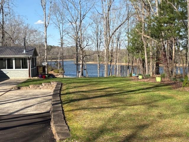 view of yard featuring a sunroom and a water view