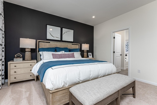 bedroom featuring light carpet, baseboards, ensuite bath, an accent wall, and recessed lighting