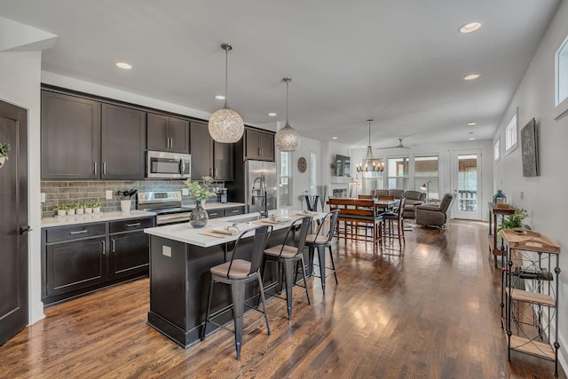 kitchen with dark wood-style floors, light countertops, appliances with stainless steel finishes, and a kitchen breakfast bar