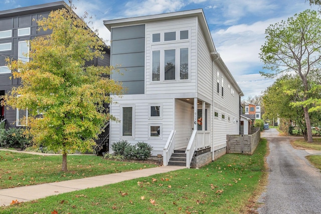 view of side of property featuring aphalt driveway and a yard