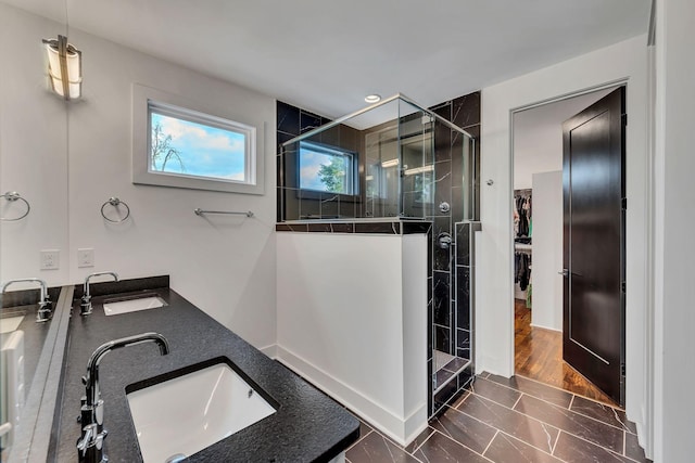 full bath featuring double vanity, a sink, and a shower stall