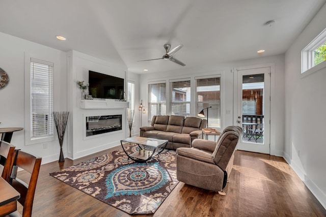 living area with wood finished floors, recessed lighting, a glass covered fireplace, and baseboards