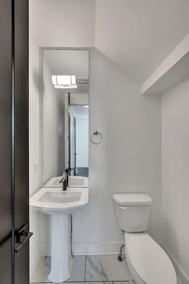 half bathroom with marble finish floor, baseboards, and toilet