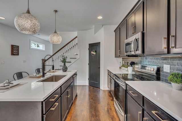 kitchen featuring dark wood-style floors, stainless steel appliances, a sink, and light countertops