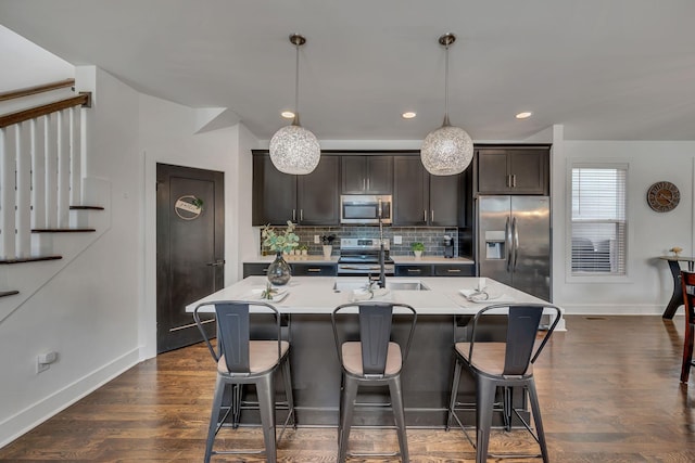 kitchen with stainless steel appliances, a breakfast bar area, an island with sink, and backsplash