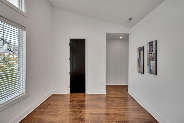 empty room with vaulted ceiling, dark wood-style flooring, a wealth of natural light, and baseboards