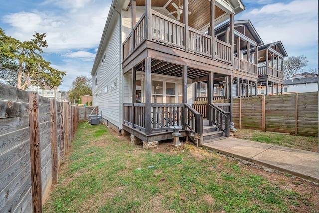 back of property featuring a fenced backyard, a lawn, a deck, and central AC