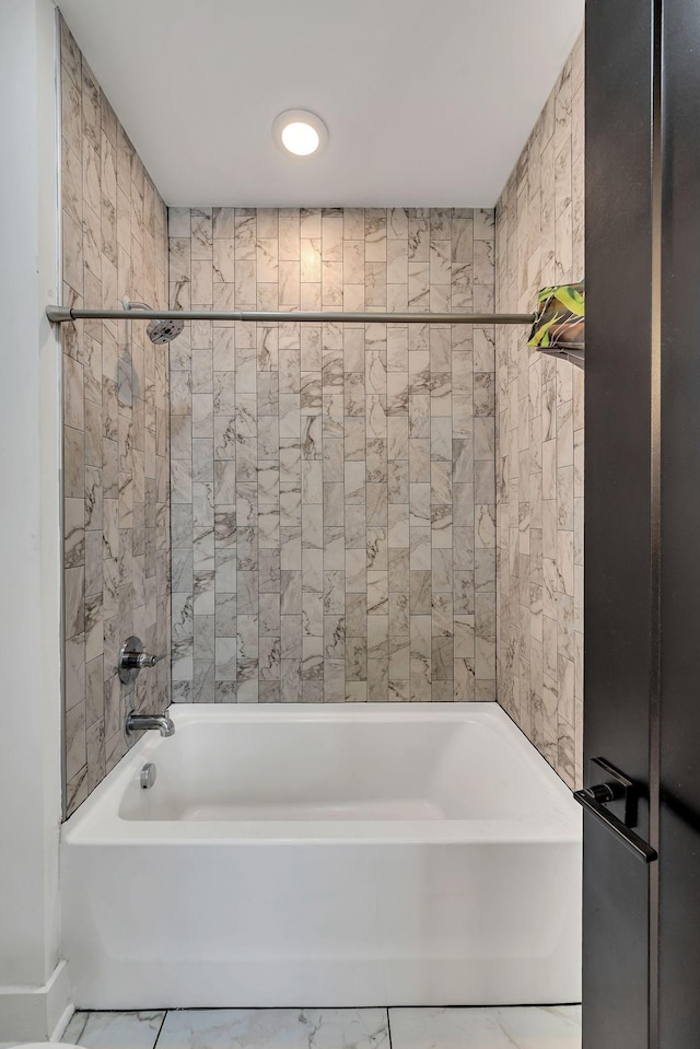 bathroom with marble finish floor and shower / washtub combination