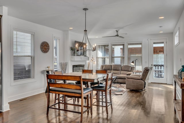 dining room featuring baseboards, visible vents, a glass covered fireplace, dark wood-style flooring, and recessed lighting