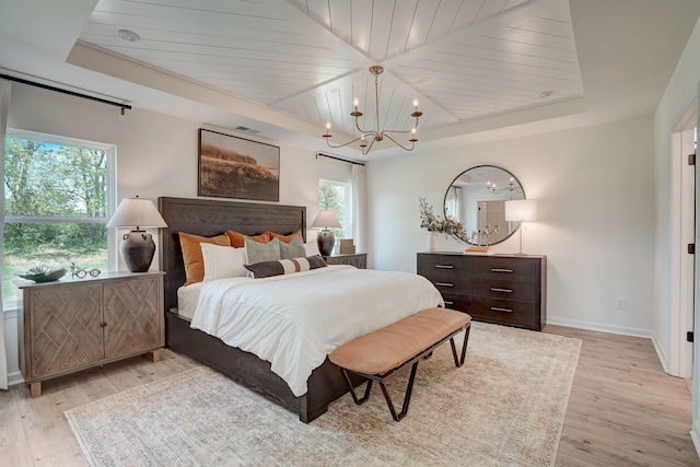 bedroom with light wood finished floors, baseboards, a raised ceiling, wood ceiling, and an inviting chandelier