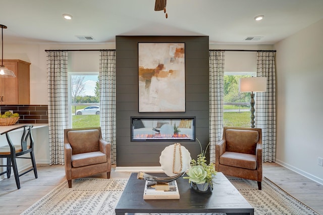 living area with baseboards, visible vents, light wood-style floors, a fireplace, and recessed lighting