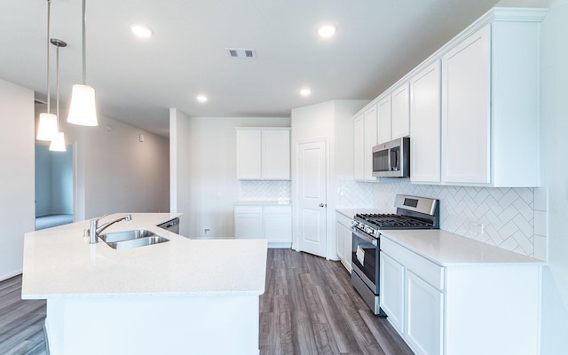 kitchen featuring visible vents, a center island with sink, dark wood-style floors, stainless steel appliances, and a sink