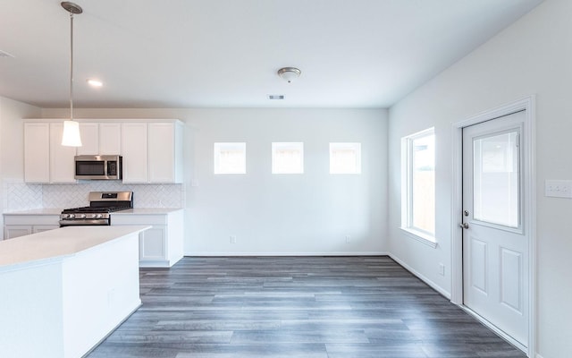 kitchen with light countertops, wood finished floors, tasteful backsplash, and stainless steel appliances