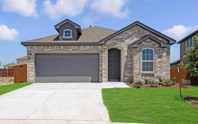 french country home with a front yard, fence, a garage, and driveway