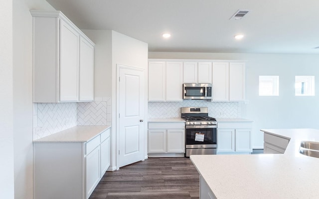 kitchen with visible vents, dark wood-style flooring, light countertops, white cabinets, and appliances with stainless steel finishes