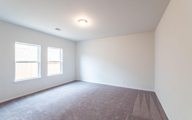 carpeted spare room featuring baseboards and visible vents