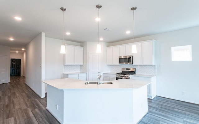 kitchen featuring a center island with sink, dark wood-style flooring, a sink, stainless steel appliances, and light countertops