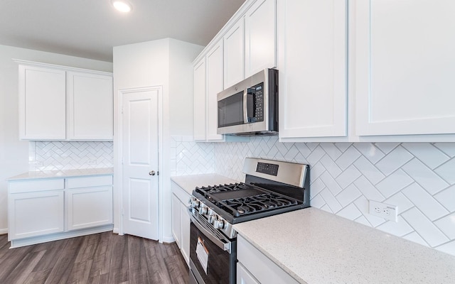 kitchen featuring white cabinetry, dark wood-type flooring, light stone countertops, and appliances with stainless steel finishes