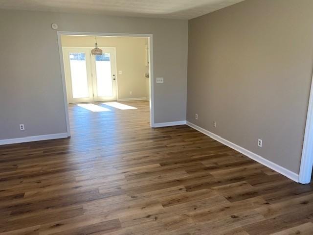 empty room with dark wood-type flooring and baseboards