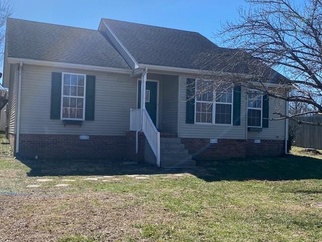 view of front of property featuring roof with shingles, crawl space, and a front yard