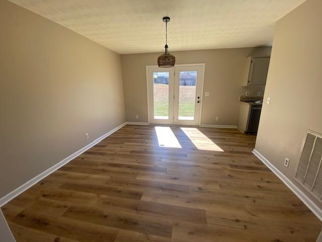 unfurnished dining area featuring visible vents, baseboards, and wood finished floors