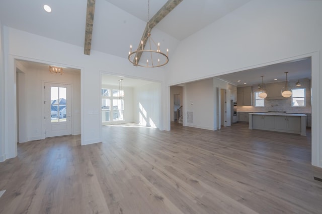 unfurnished living room featuring a healthy amount of sunlight, light wood-style flooring, visible vents, and a chandelier