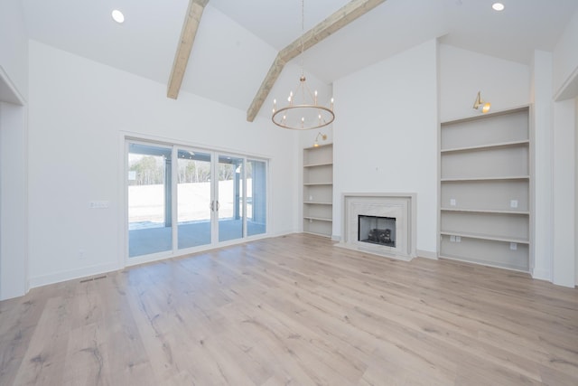 unfurnished living room with beamed ceiling, an inviting chandelier, light wood-style floors, high vaulted ceiling, and a high end fireplace