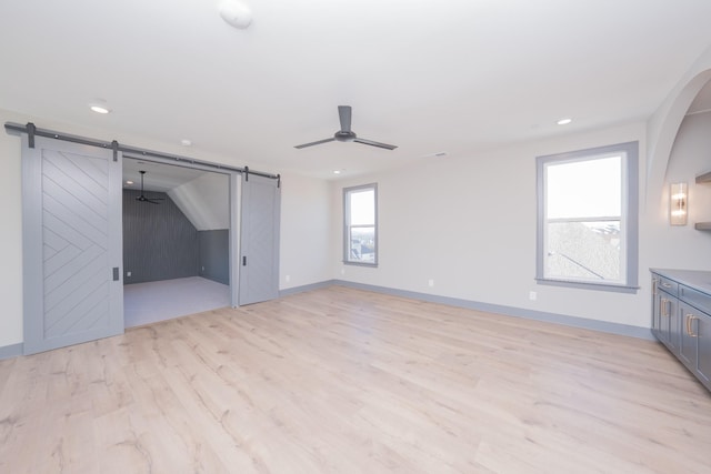 unfurnished bedroom featuring recessed lighting, a barn door, ceiling fan, light wood-type flooring, and baseboards