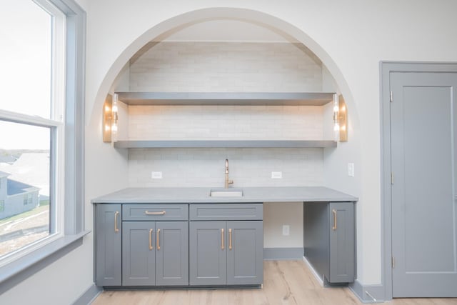 kitchen featuring decorative backsplash, open shelves, a sink, and gray cabinetry