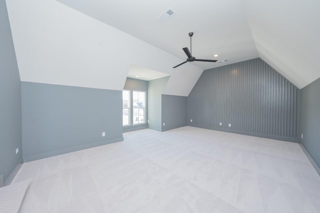 bonus room featuring lofted ceiling, light colored carpet, visible vents, a ceiling fan, and baseboards