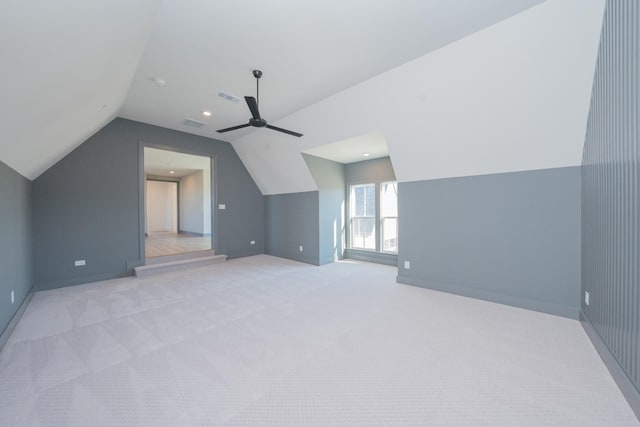 additional living space with lofted ceiling, visible vents, ceiling fan, and light carpet