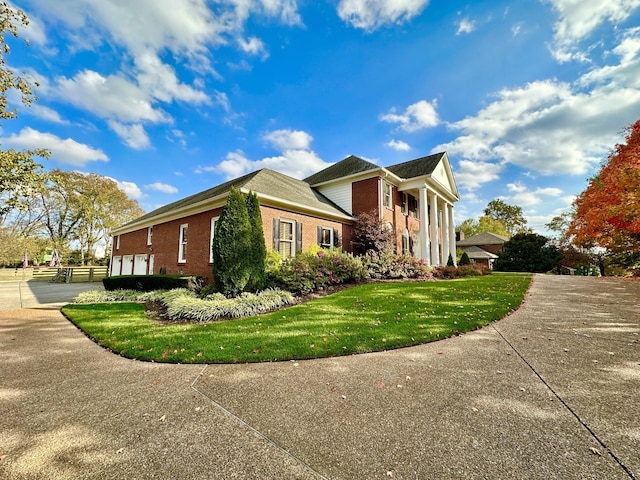 view of side of home featuring concrete driveway, brick siding, and a lawn