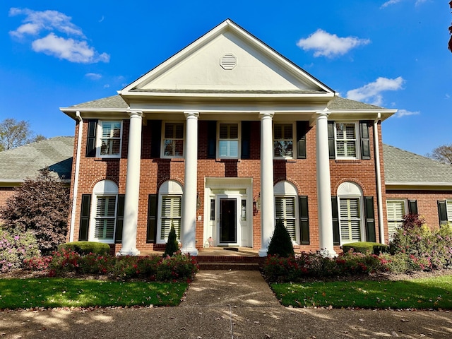 neoclassical home with a shingled roof and brick siding