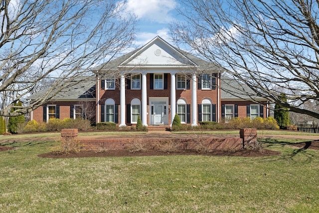 neoclassical home with brick siding and a front lawn