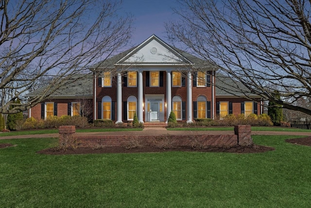 neoclassical home featuring brick siding and a lawn