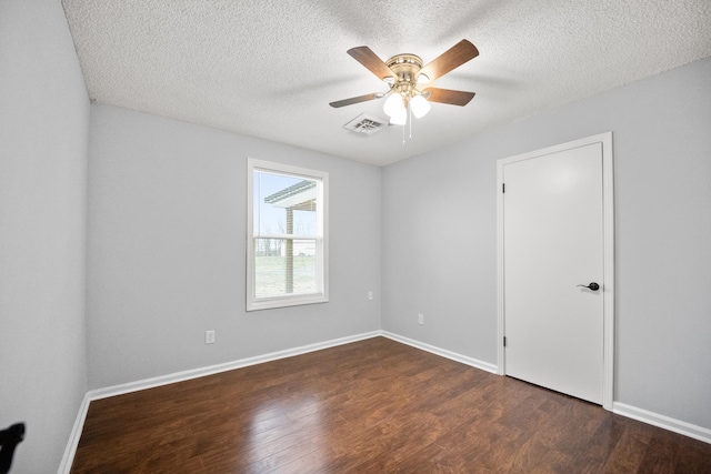 unfurnished room featuring dark wood-style floors, baseboards, visible vents, and ceiling fan