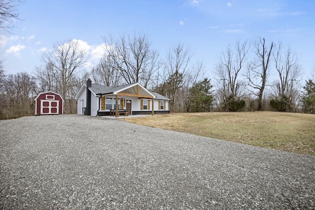 view of front of home featuring a chimney, a porch, a storage shed, an outdoor structure, and a front lawn