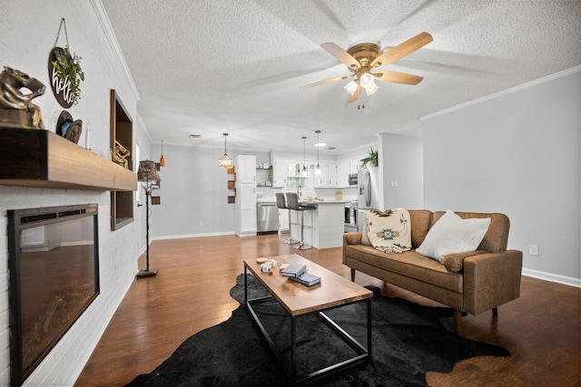 living room with ornamental molding, ceiling fan, a textured ceiling, and light wood finished floors