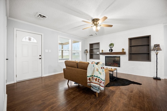 living room with visible vents, a glass covered fireplace, a textured ceiling, and wood finished floors