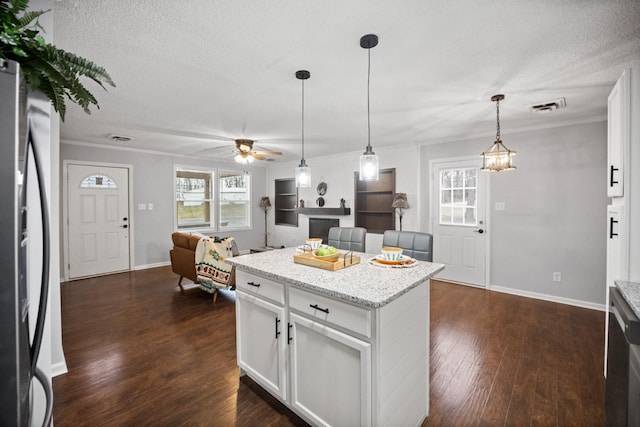 kitchen with visible vents, dark wood-type flooring, freestanding refrigerator, hanging light fixtures, and a textured ceiling