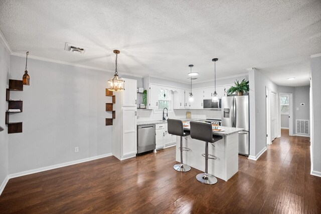 kitchen featuring stainless steel appliances, a center island, visible vents, and white cabinetry