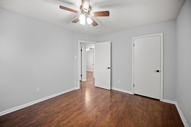 unfurnished bedroom with a textured ceiling, baseboards, and wood finished floors