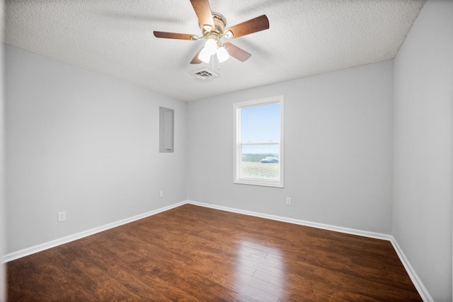 spare room featuring dark wood-type flooring, visible vents, a textured ceiling, and baseboards