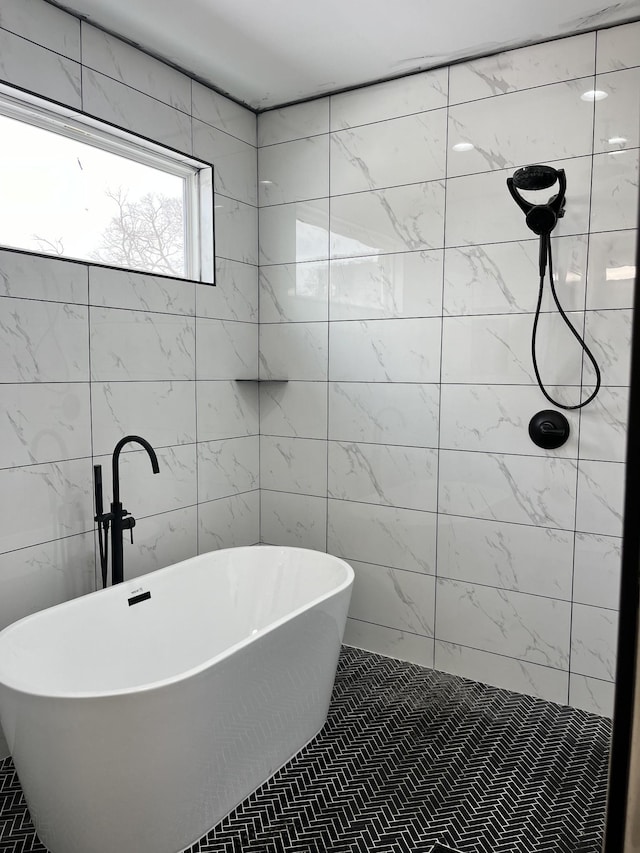 bathroom with tile walls, a tile shower, and a freestanding bath