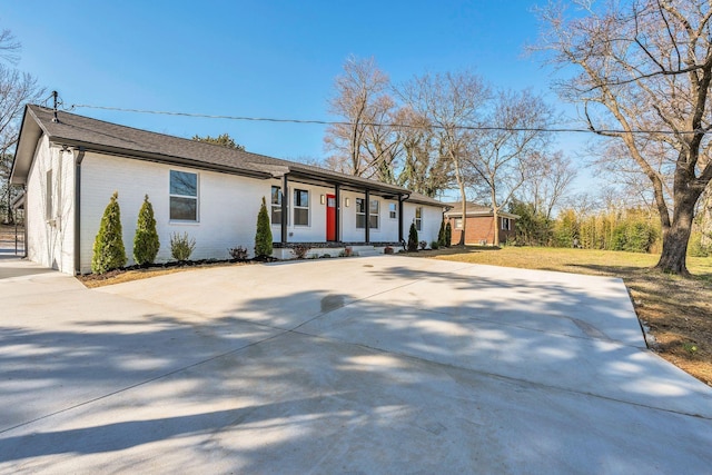 ranch-style house with concrete driveway, brick siding, and a front lawn