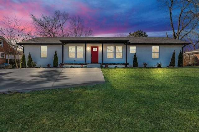 ranch-style home featuring a lawn and brick siding