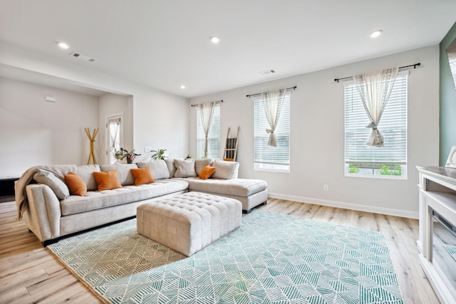 living area with light wood-type flooring, visible vents, baseboards, and recessed lighting