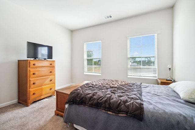 bedroom with baseboards, visible vents, and light colored carpet