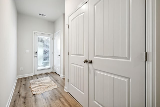 doorway with visible vents, baseboards, and wood finished floors