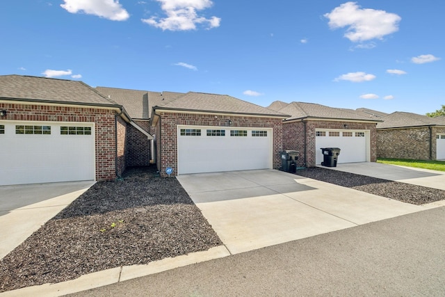 view of front of property featuring an attached garage, a shingled roof, concrete driveway, and brick siding